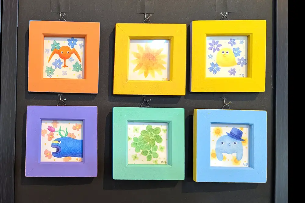 カラフルな額に入った小さな作品が並ぶ様子