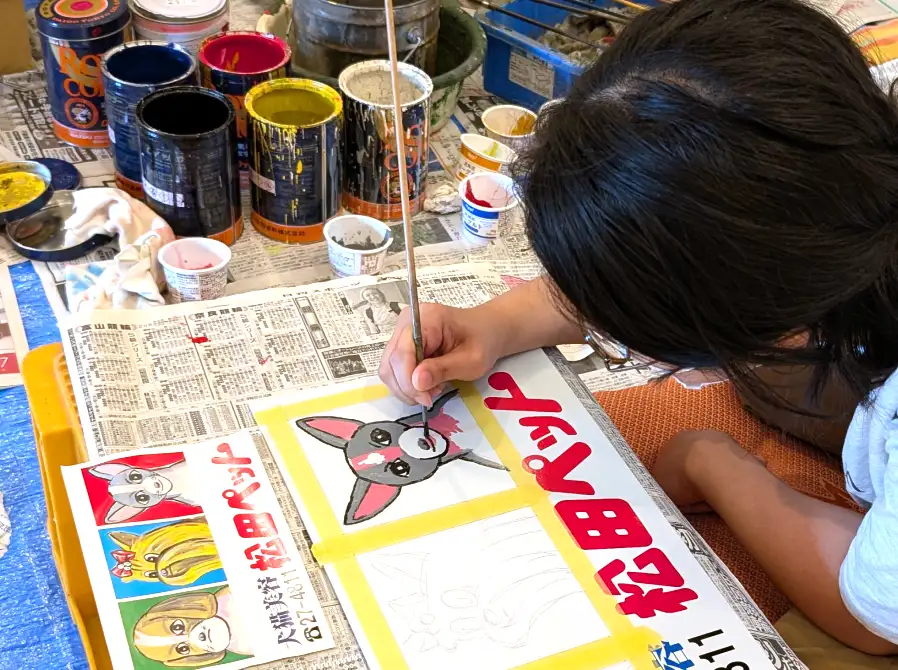 筆とペンキを使って松田ペットのミニ看板を制作する様子