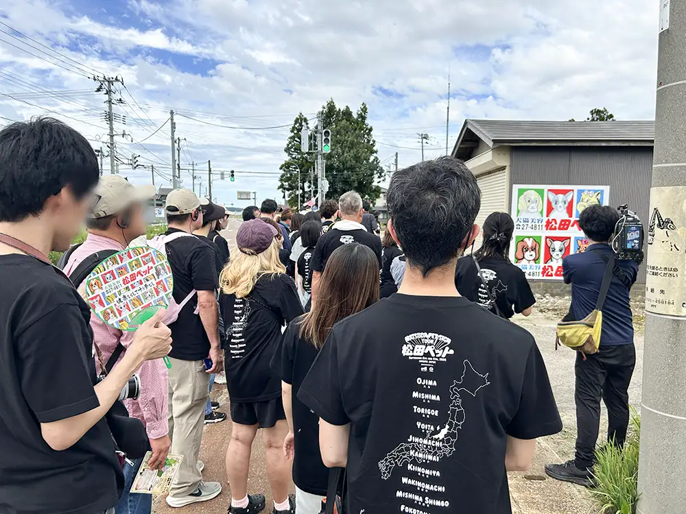 「例の看板」にカメラを向けるバスツアー参加者