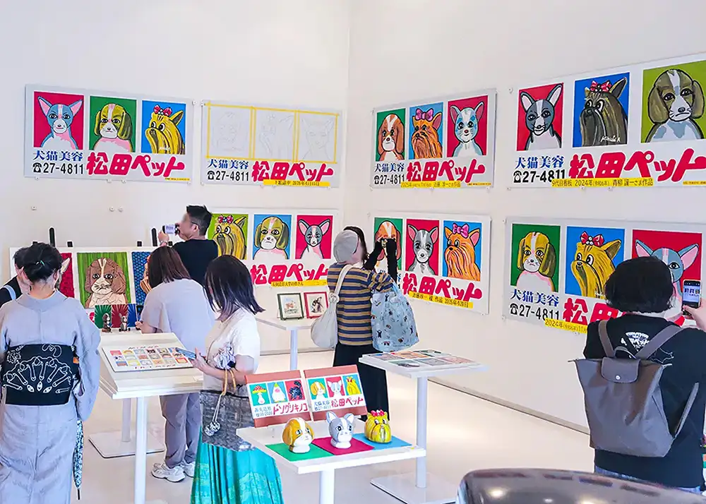 本家の松田ペット看板とオマージュ作品を鑑賞する来場者